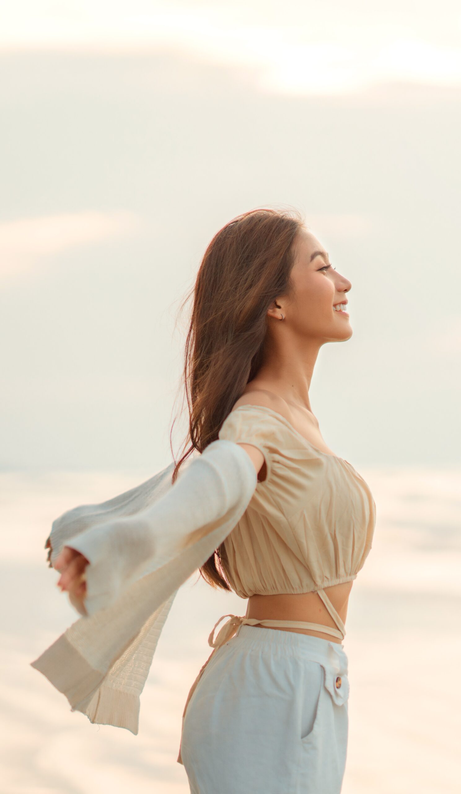 Happy free woman arms out on beach